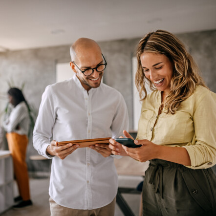 Un courtier en assurance souriant avec une cliente, discutant dans un bureau moderne et collaboratif
